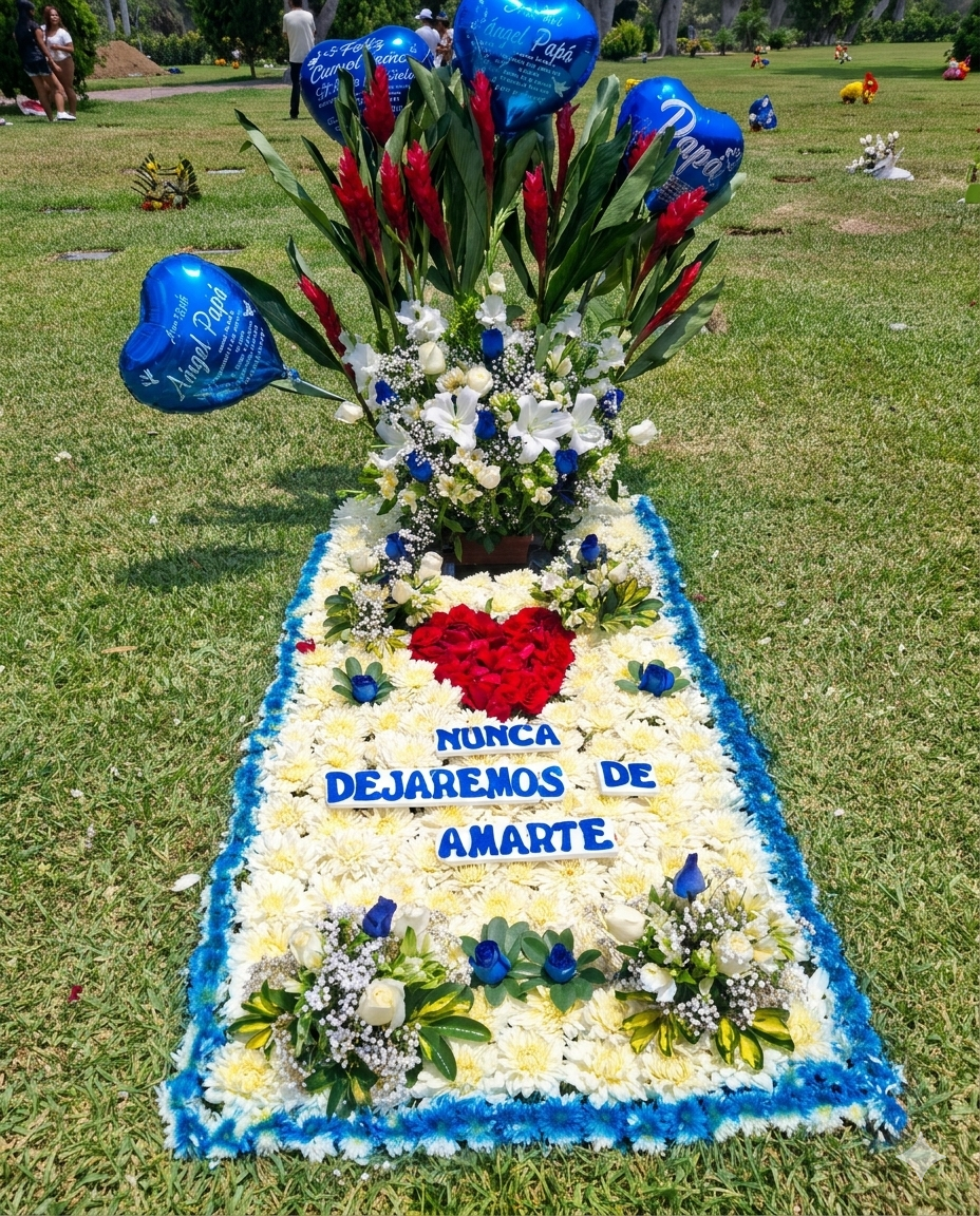 Impresionante tapiz floral rectangular con bordes azules y corazón central de rosas rojas, coronado por un arreglo de heliconias, lirios y globos azules personalizados.