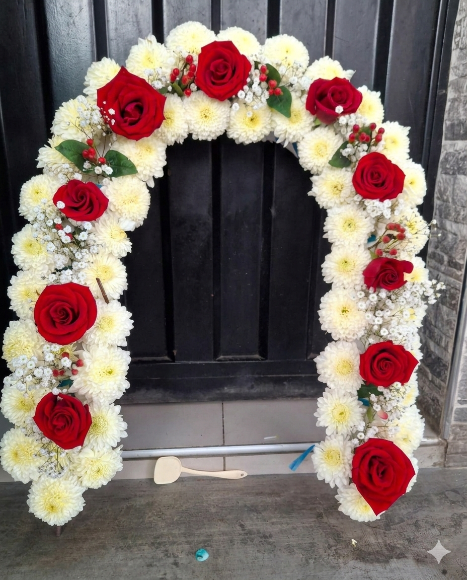 Clásico arco floral de pompones blancos y rosas rojas premium, decorado con delicadas bayas de hipericum y nube.