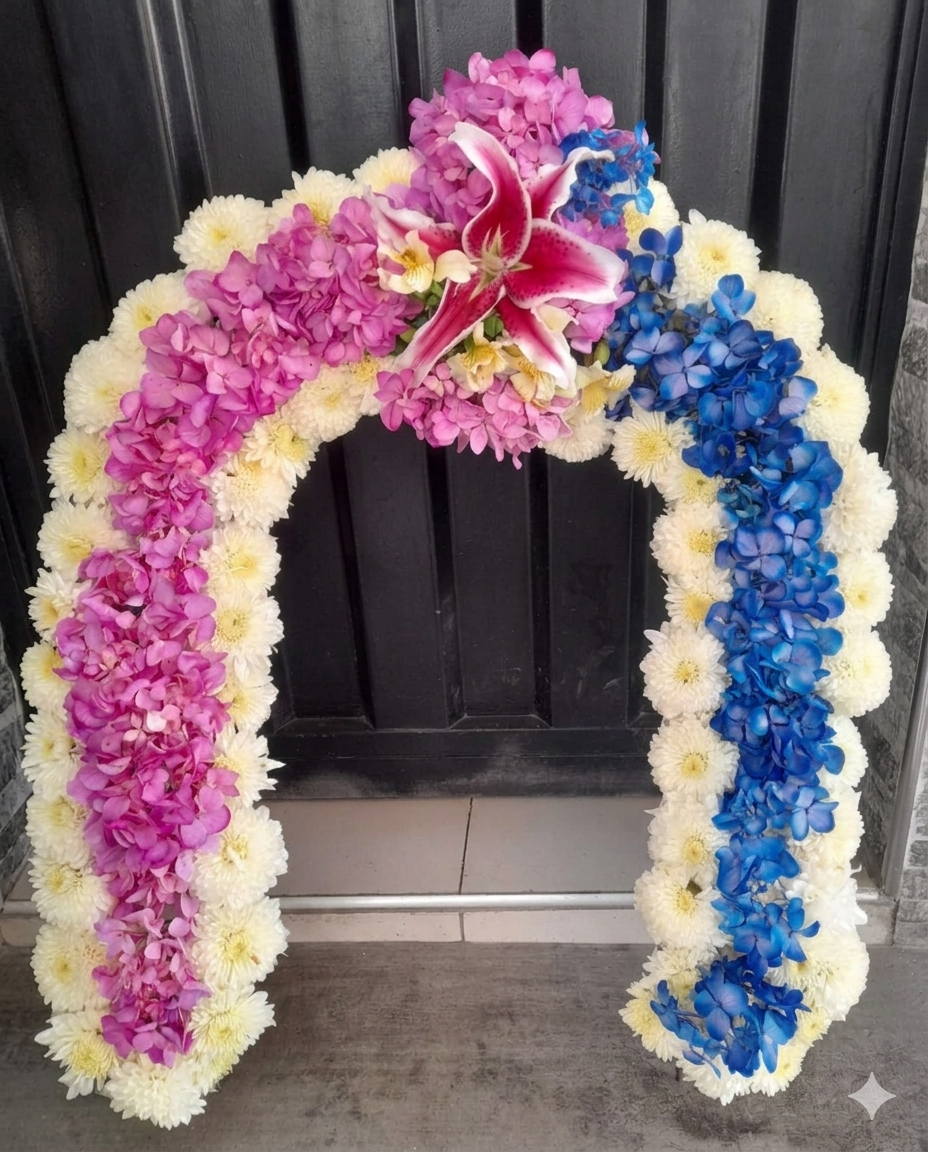 Espectacular arco floral con base de pompones blancos y un degradado de hortensias fucsias y azules, coronado por un majestuoso lirio central.